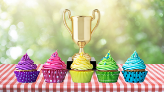 Photo of decorated cupcakes on a picnic table with a trophy.
