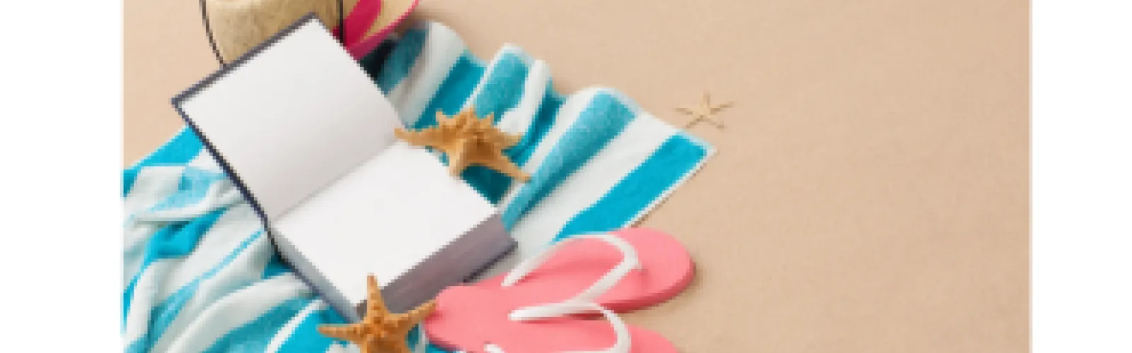 Book open on a blue and white beach towel with pink flip flops
